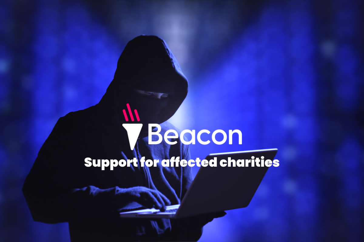 A hooded figure holds a laptop in a server room to depict a data hack at Beacon CRM